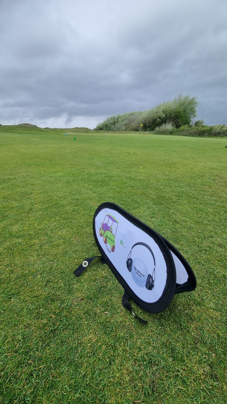 Open grassy golf course with blue and green markers in the distance and a shopping bag-style item in the foreground, under a cloudy sky.