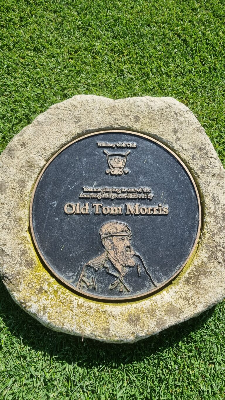 Circular bronze plaque set in a stone, on a grassy surface, honoring Old Tom Morris at Wallasey Golf Club.
