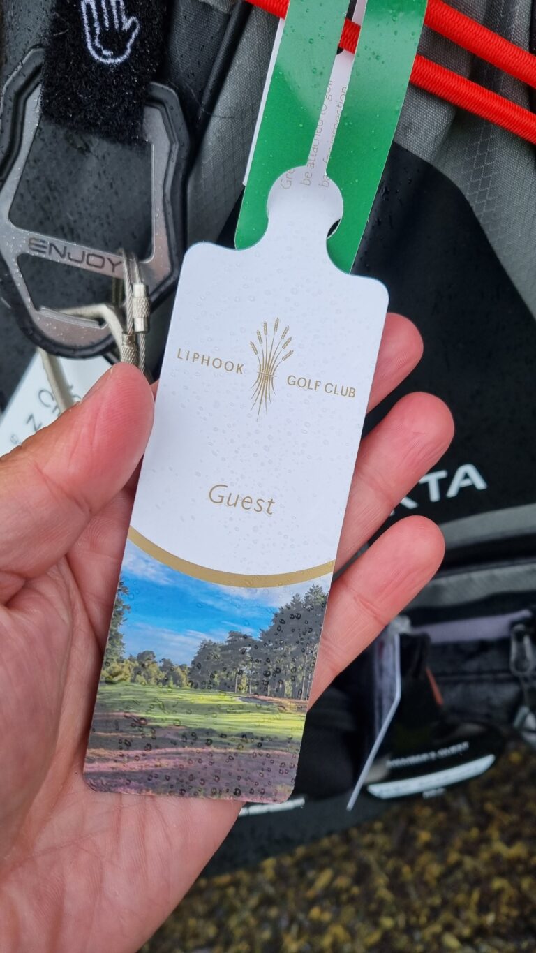 Guest badge for Liphook Golf Club on a green lanyard, held in a hand with raindrops on the badge surface.